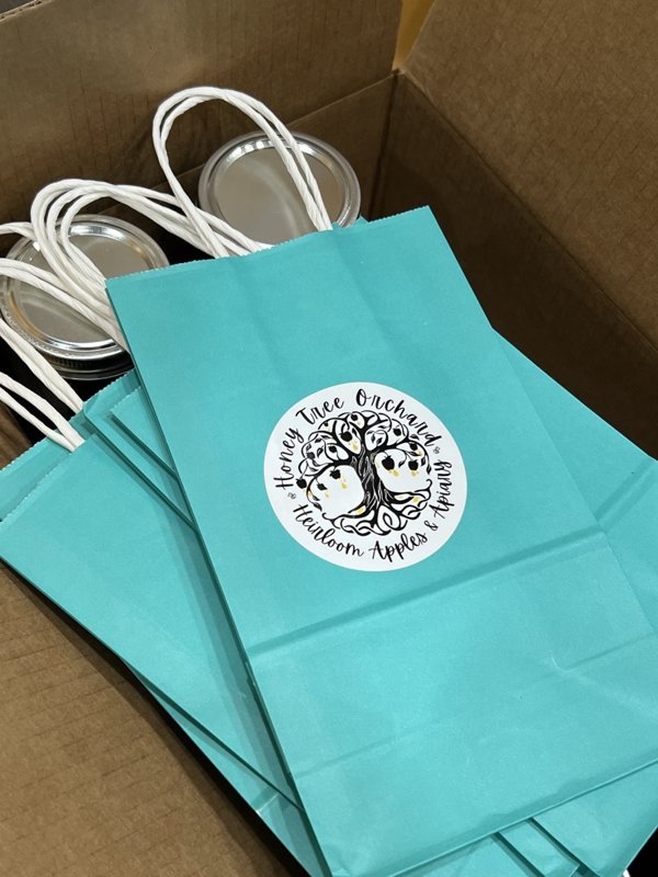 Teal gift bags with the Honey Tree Orchard logo