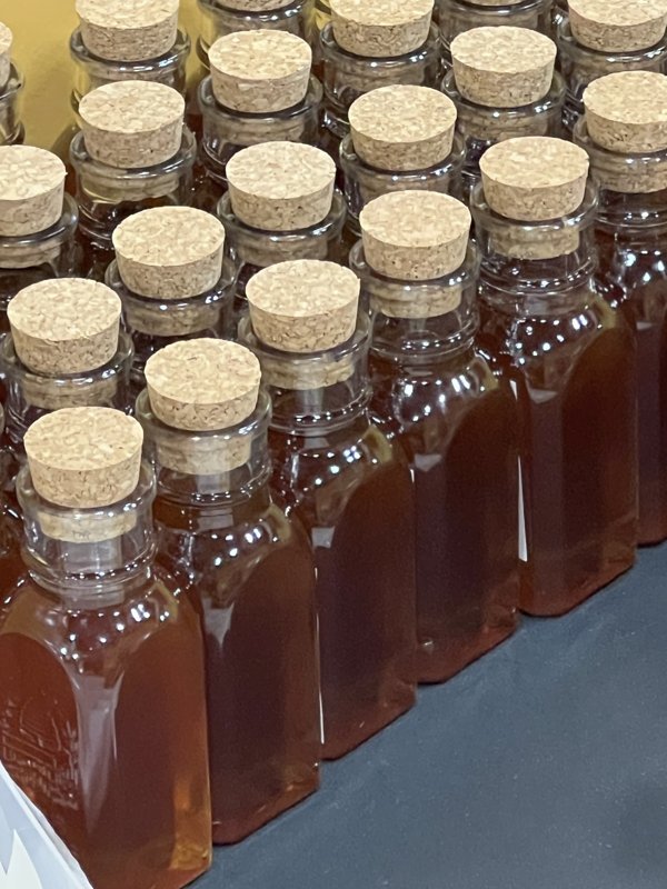 Rows of corked bottles of golden raw, strained honey
