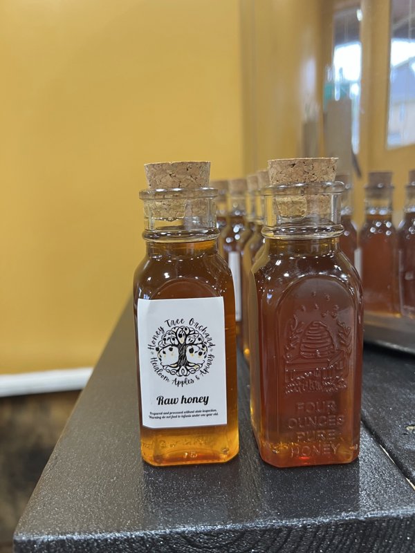 Corked bottles of raw honey with the Honey Tree Orchard label